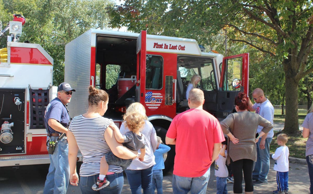 People gathered around a fire truck with "First In Last Out" on the side
