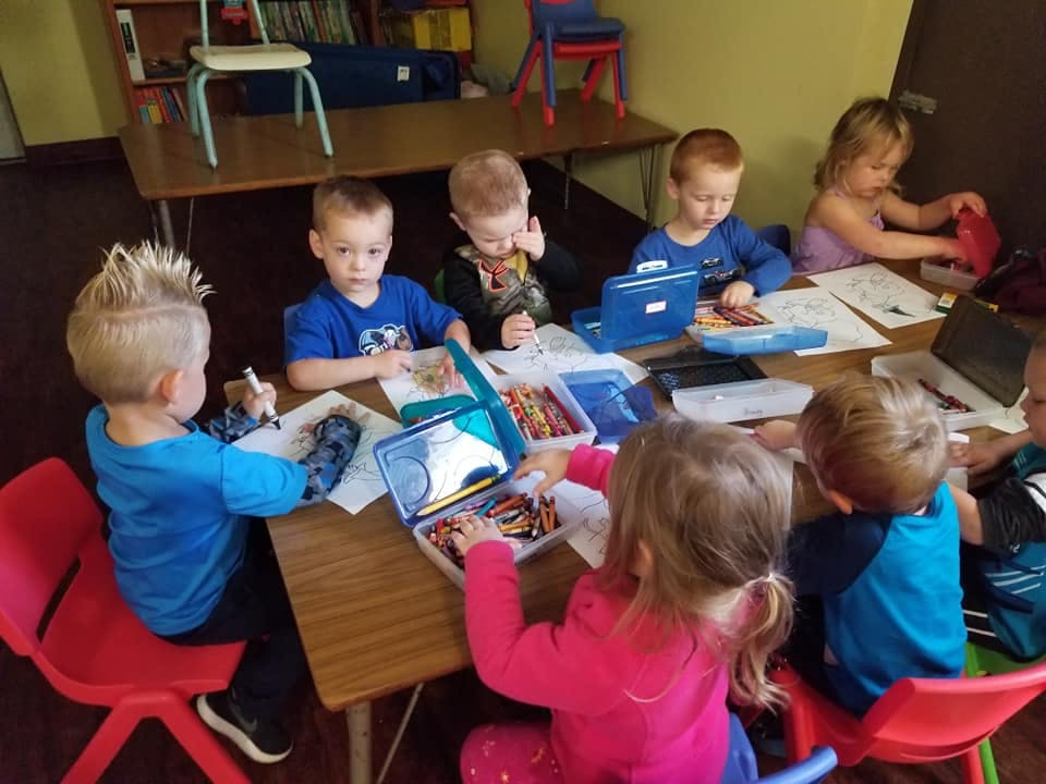 Children sitting at a table with art supplies