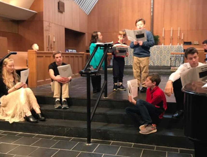 People and children holding papers in a church