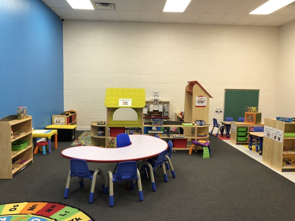 Empty classroom with small tables and chairs, shelves, and play structures