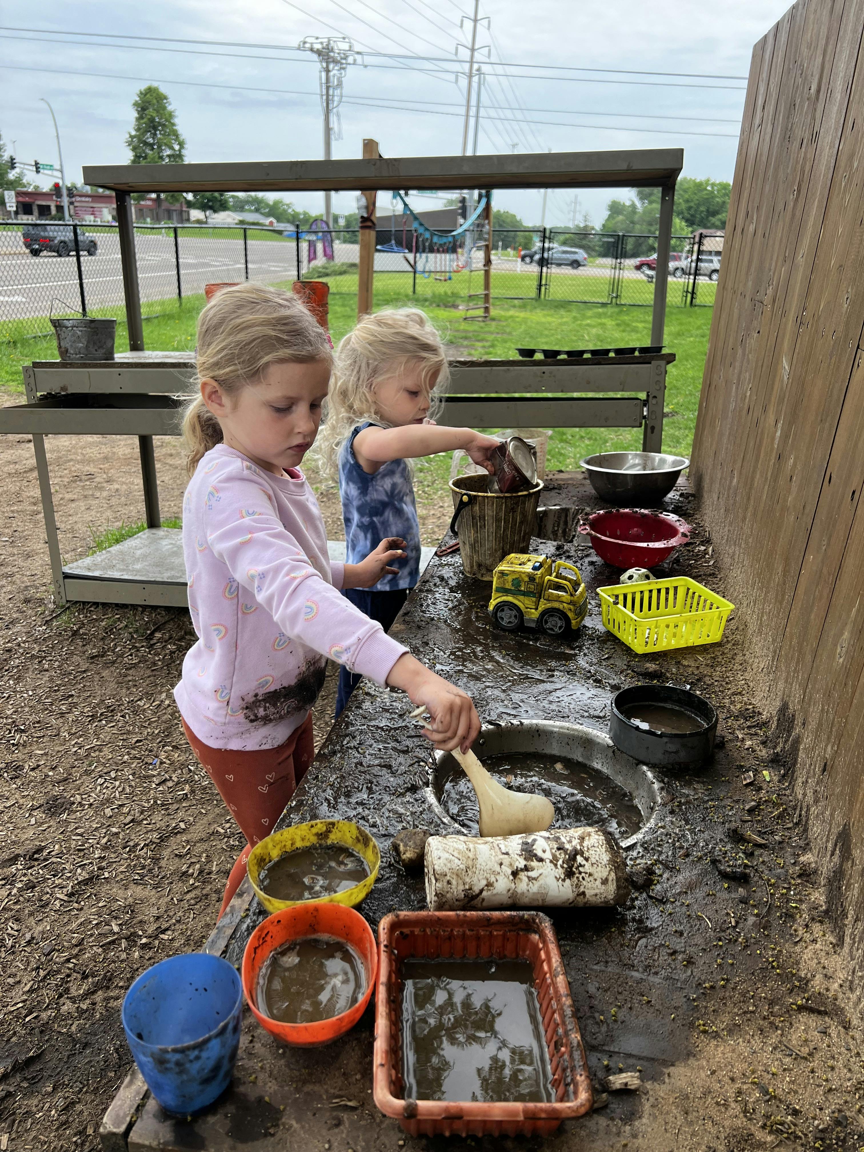 Two children playing with mud and water in various containers