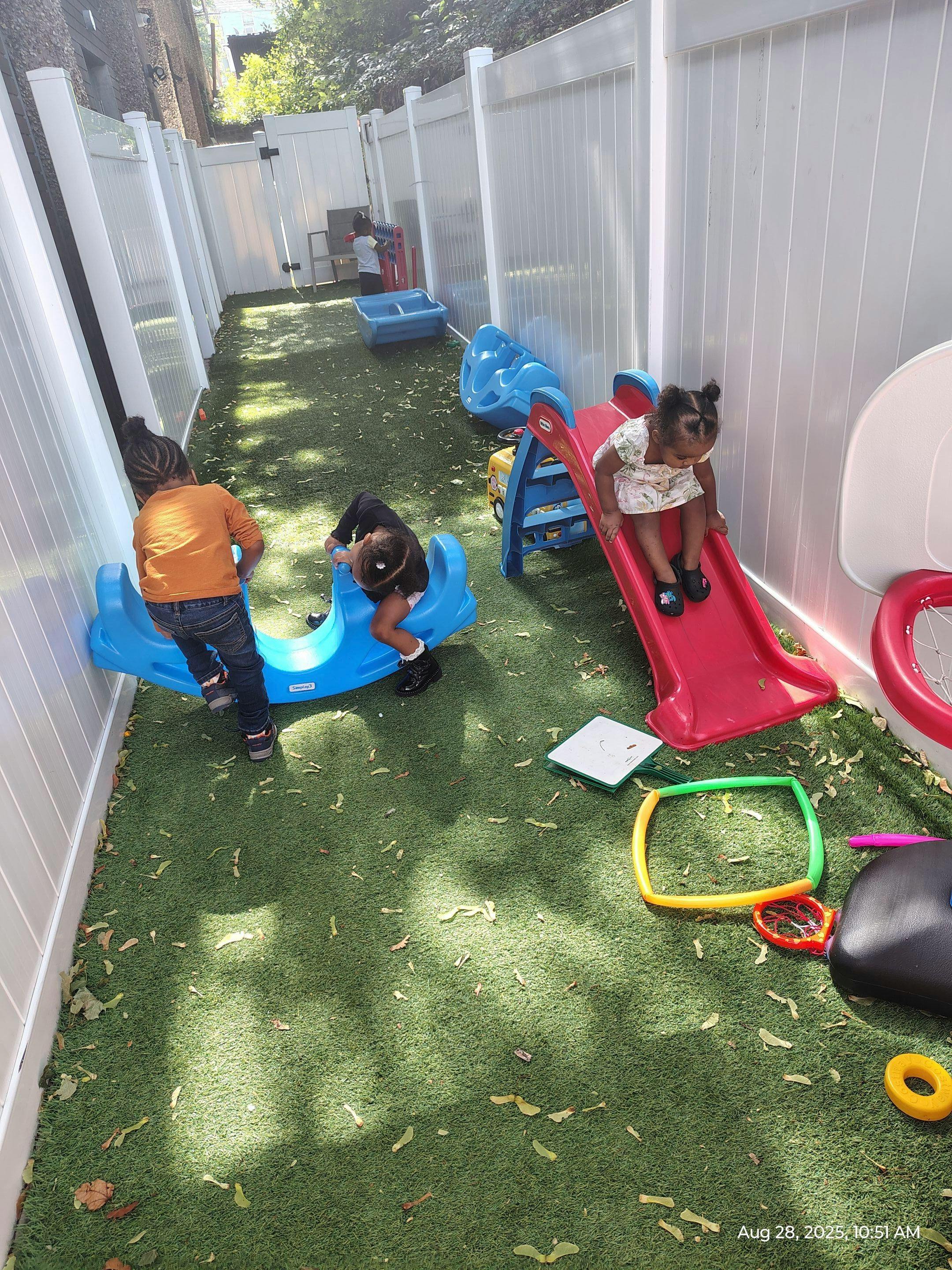 Children playing on a slide and a rocking toy on artificial grass
