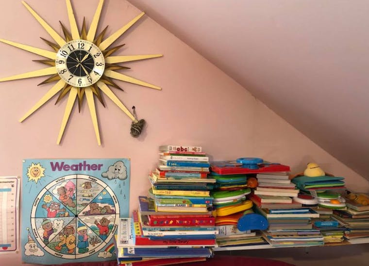 Sunburst clock on a wall above a weather chart and stacks of books