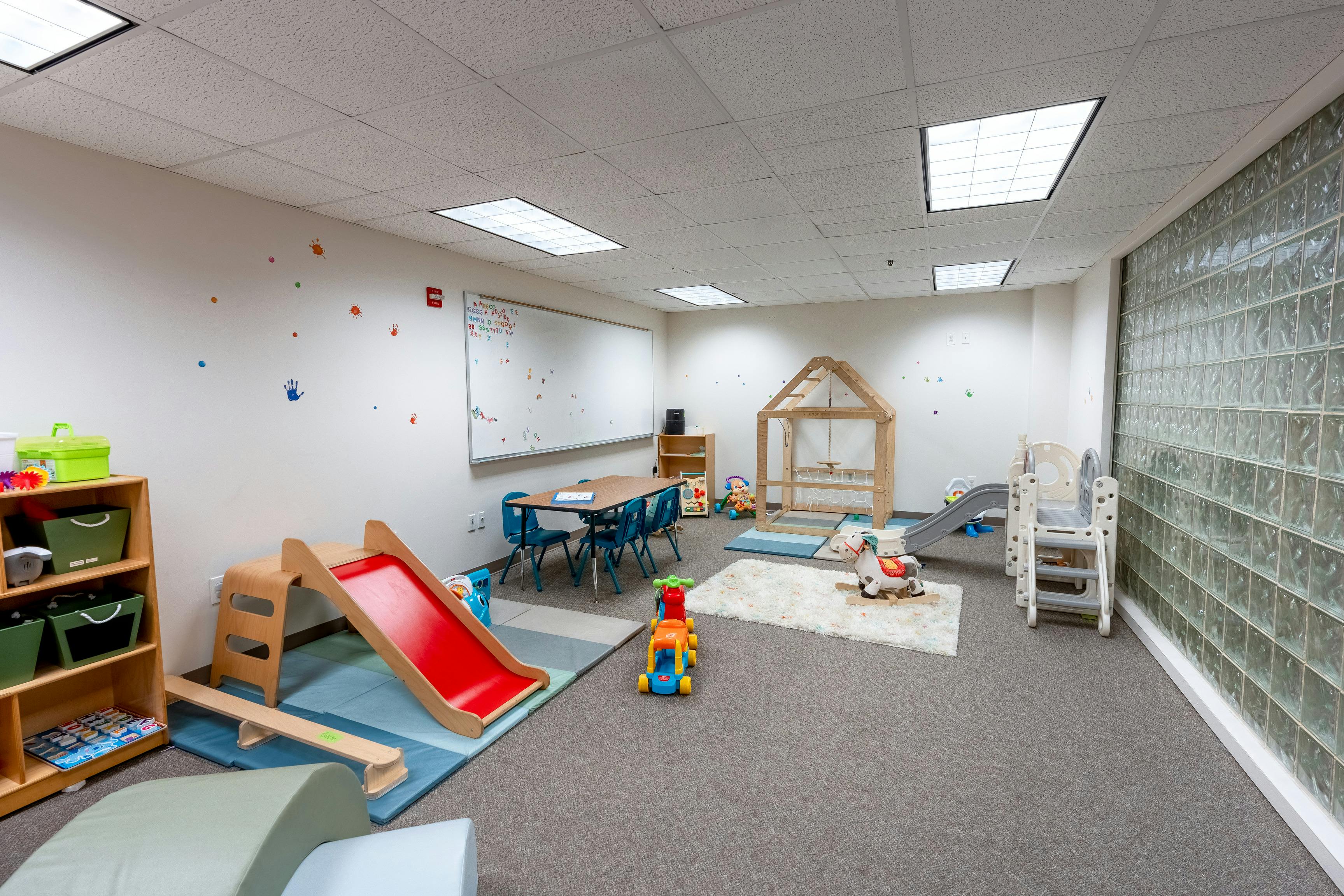 Playroom with a red slide, small table and chairs, and various toys