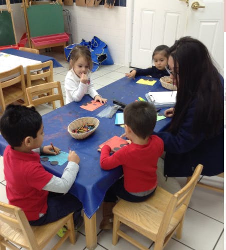 Adult and three children sitting at a table doing crafts
