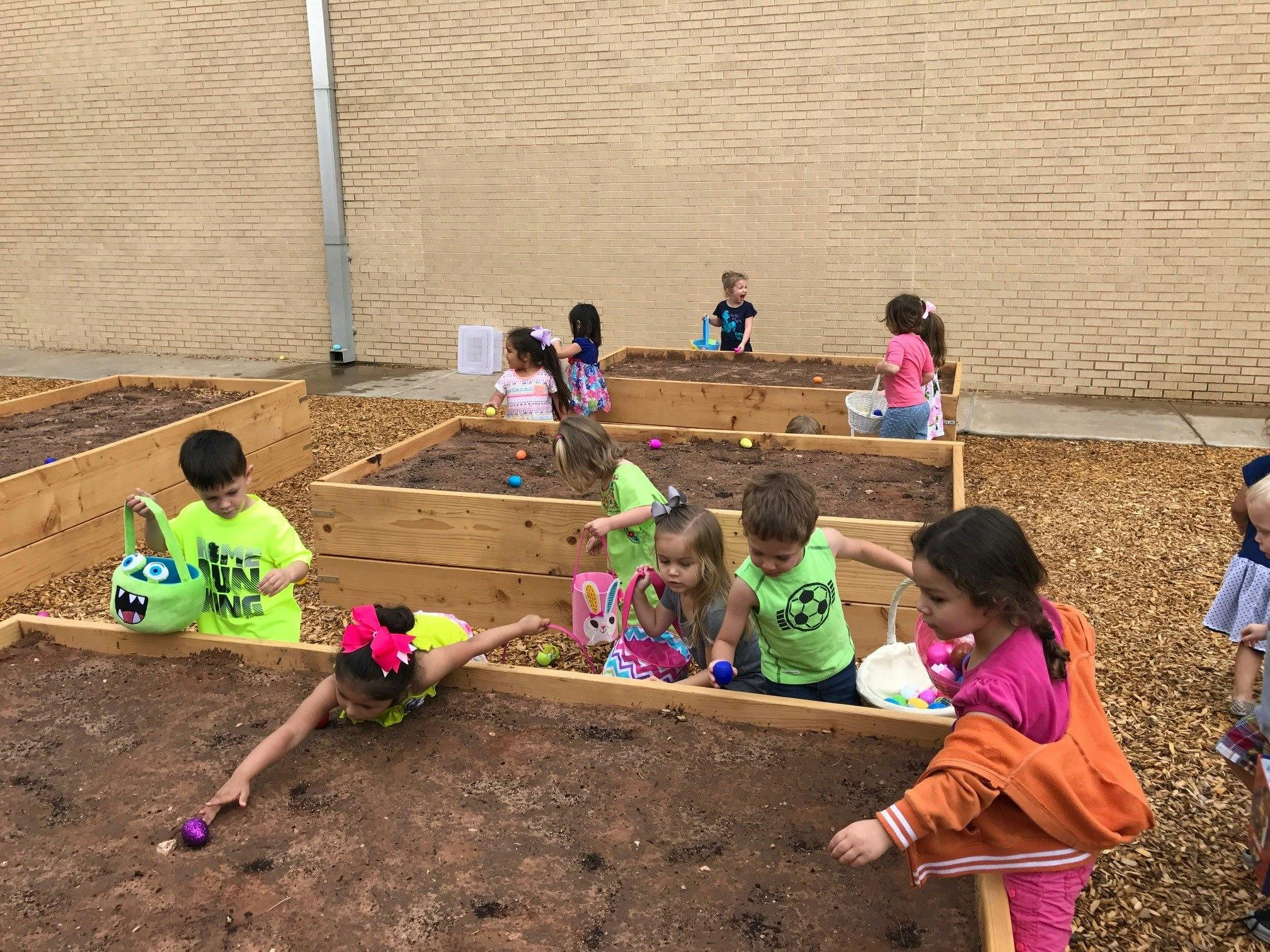 Children searching for eggs in raised garden beds