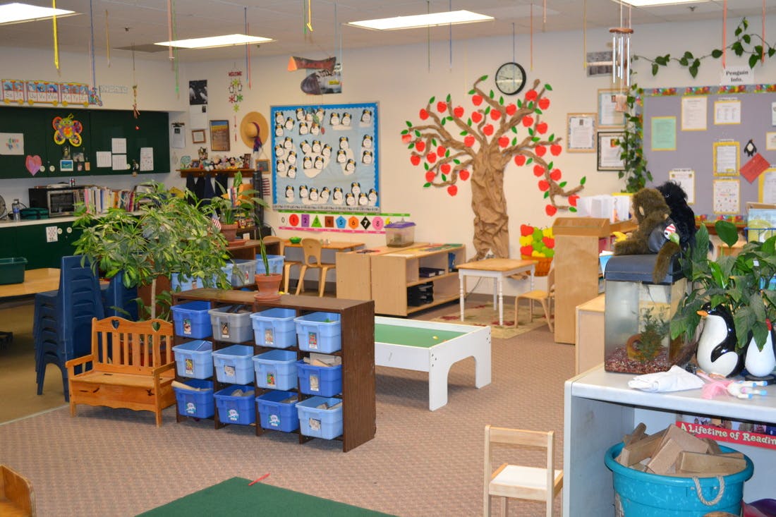 Classroom with tables, chairs, storage bins, and wall decorations