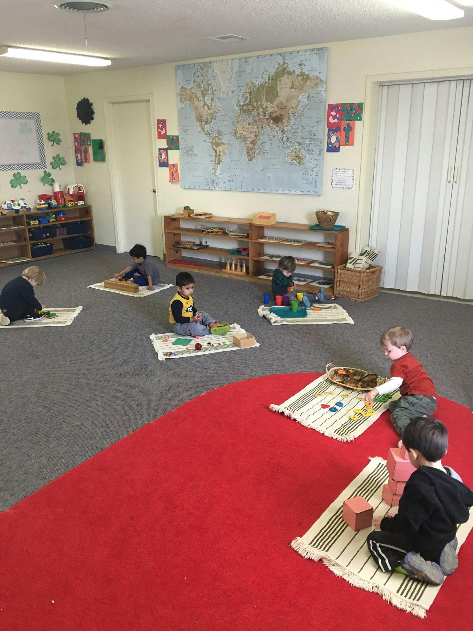 Children playing with educational toys on mats in a classroom