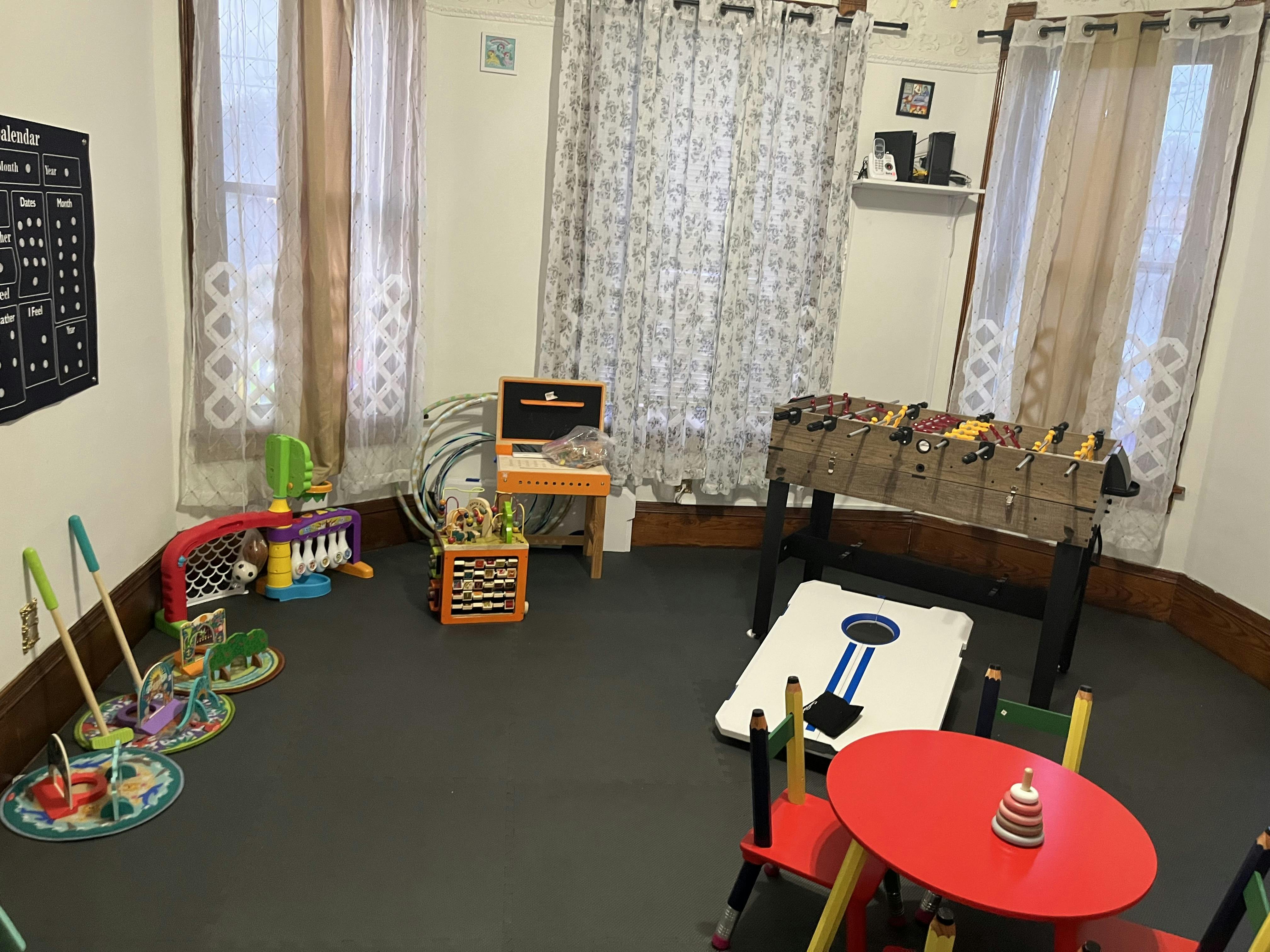 Playroom with a foosball table, small red table and chairs, and various toys