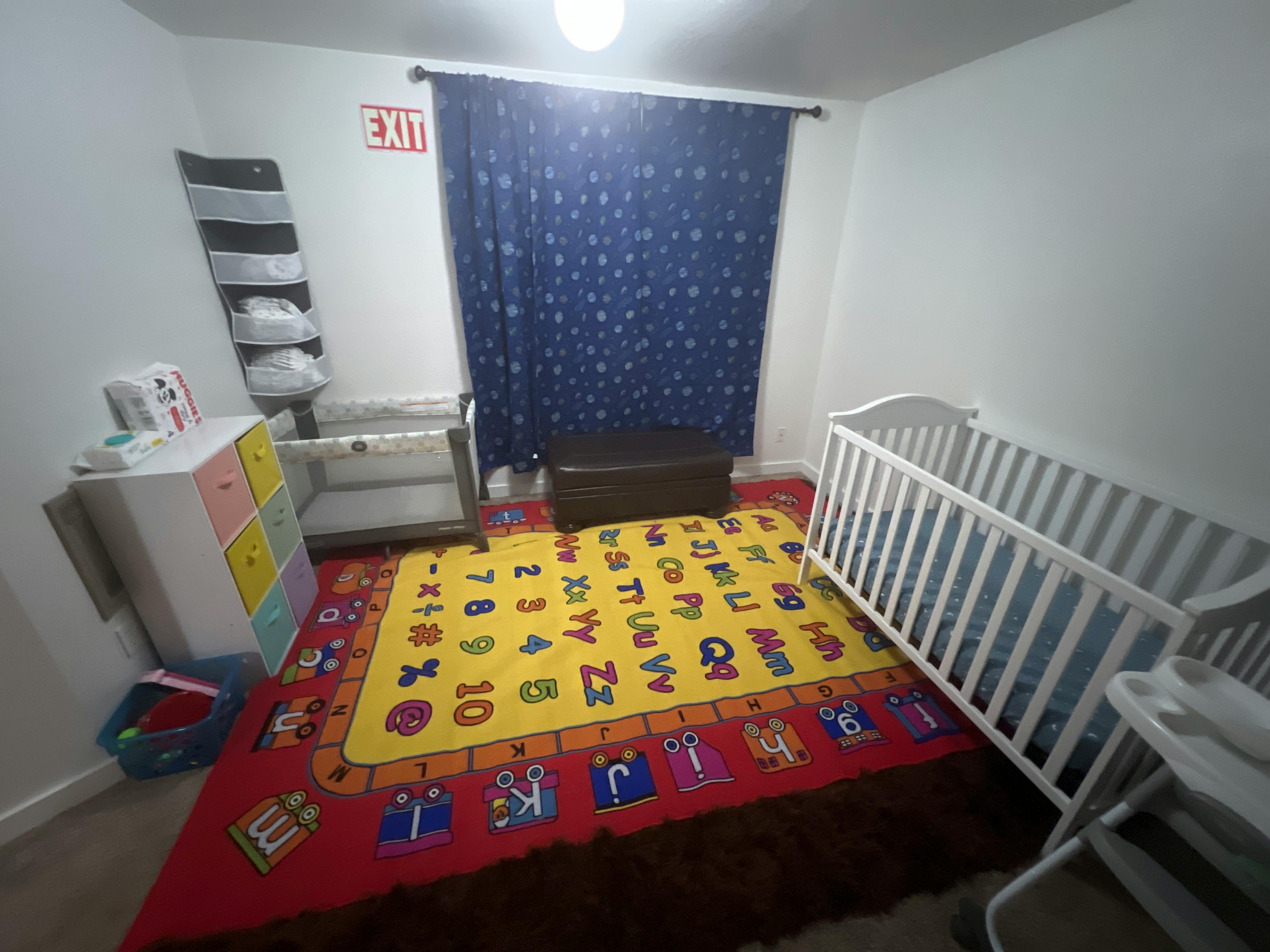 Nursery room with two cribs and an alphabet rug
