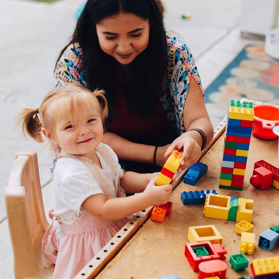 Adult and child playing with colorful building blocks at a table