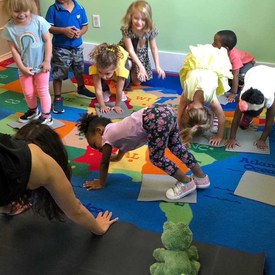 Children and an adult doing yoga poses on mats