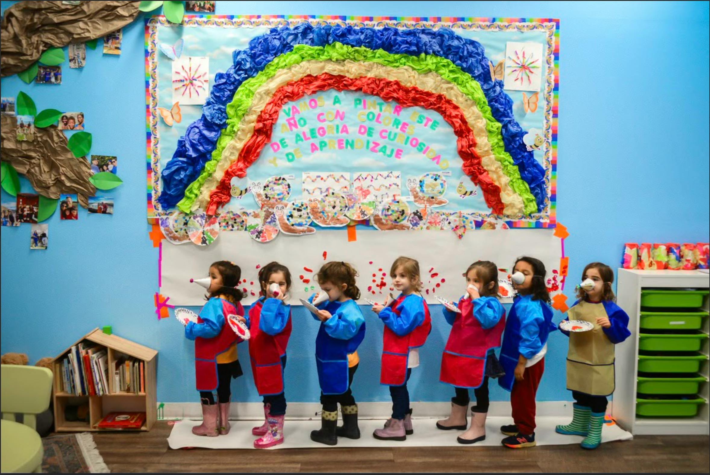 Children in aprons and masks standing in a line in a classroom