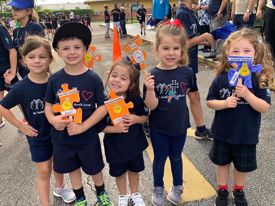 Five children holding orange puzzle piece cutouts