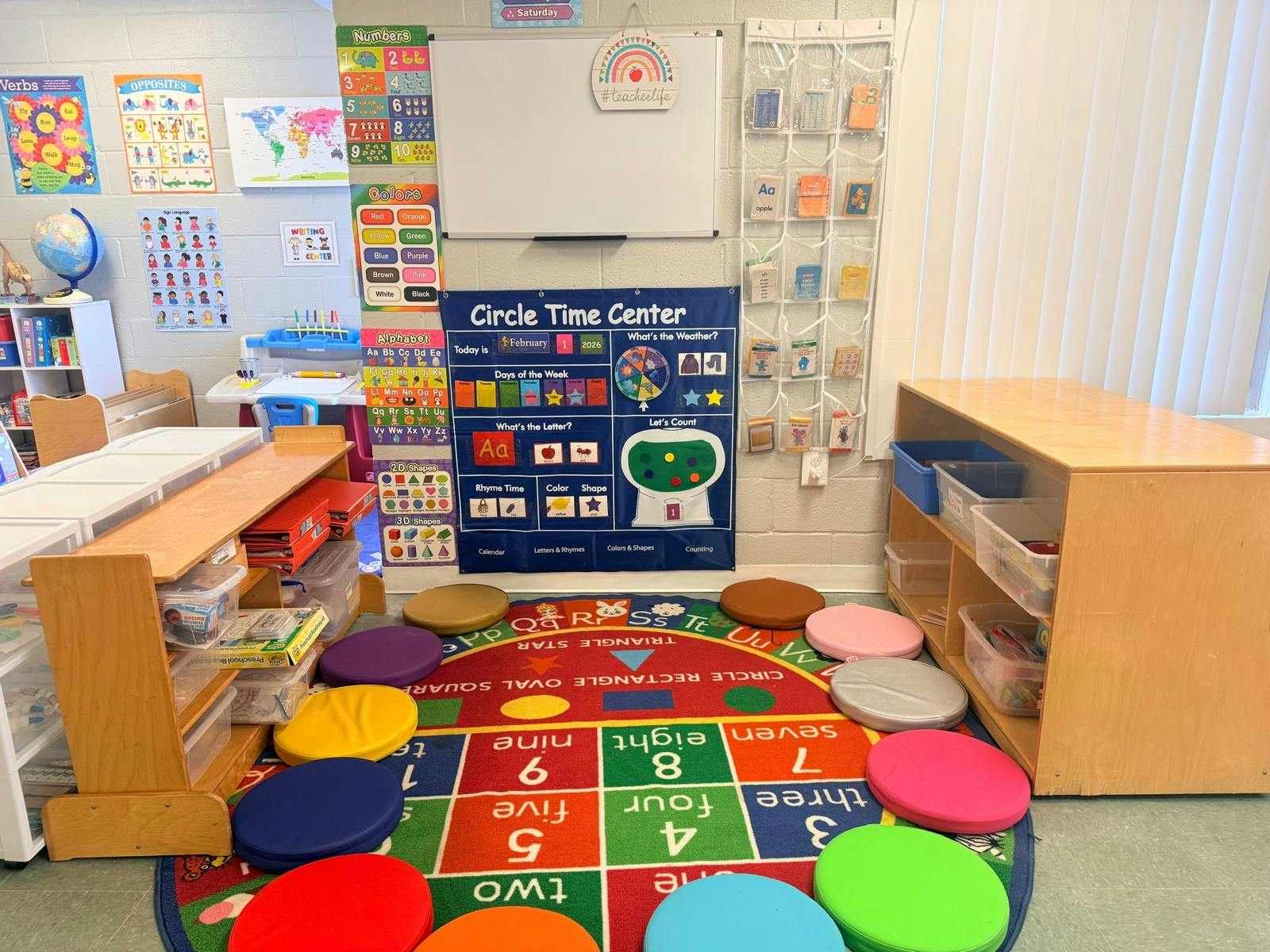 Classroom circle time area with a calendar, learning charts, and floor cushions