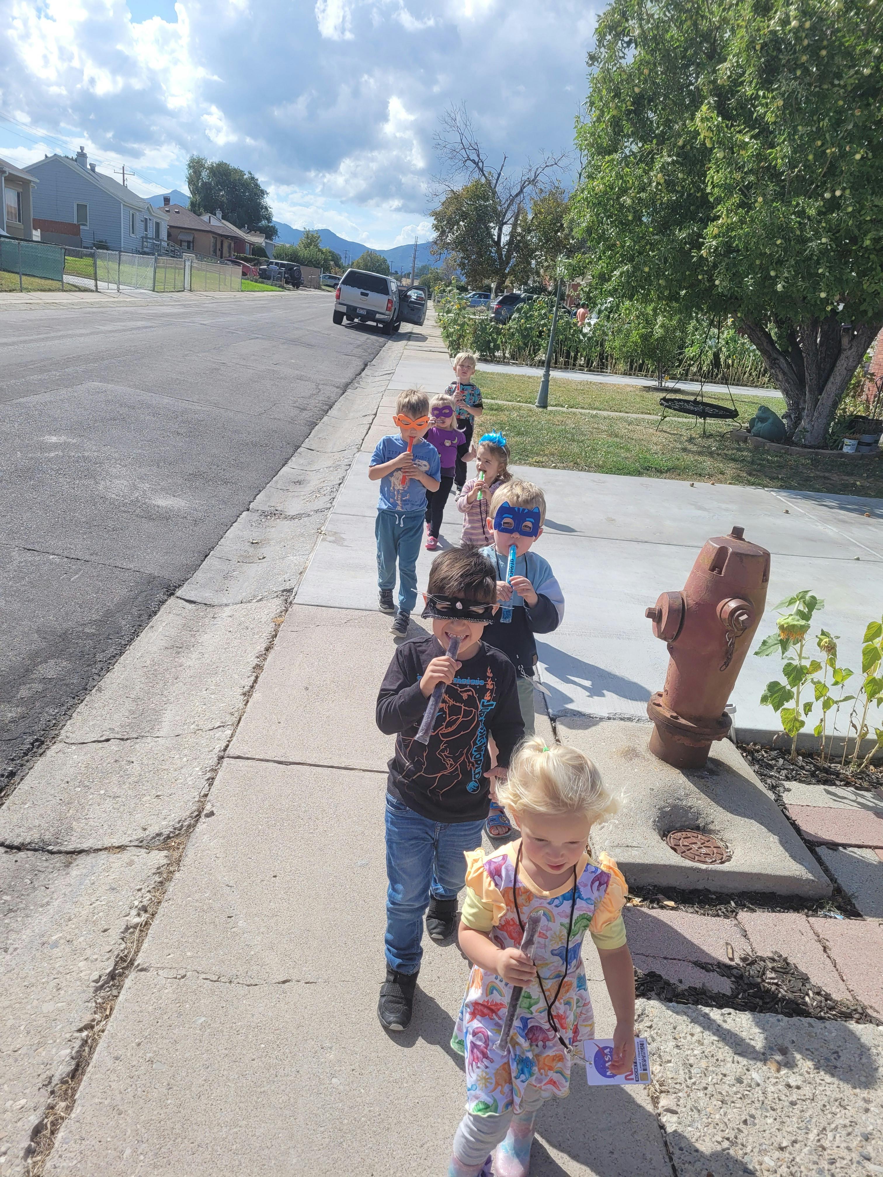 Children walking in a line on a sidewalk
