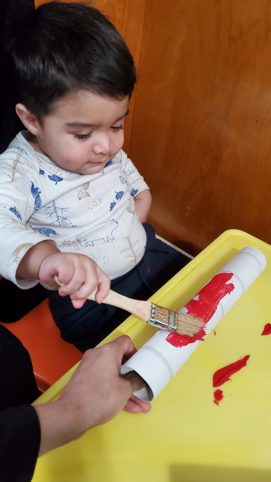 Child painting a white tube with red paint