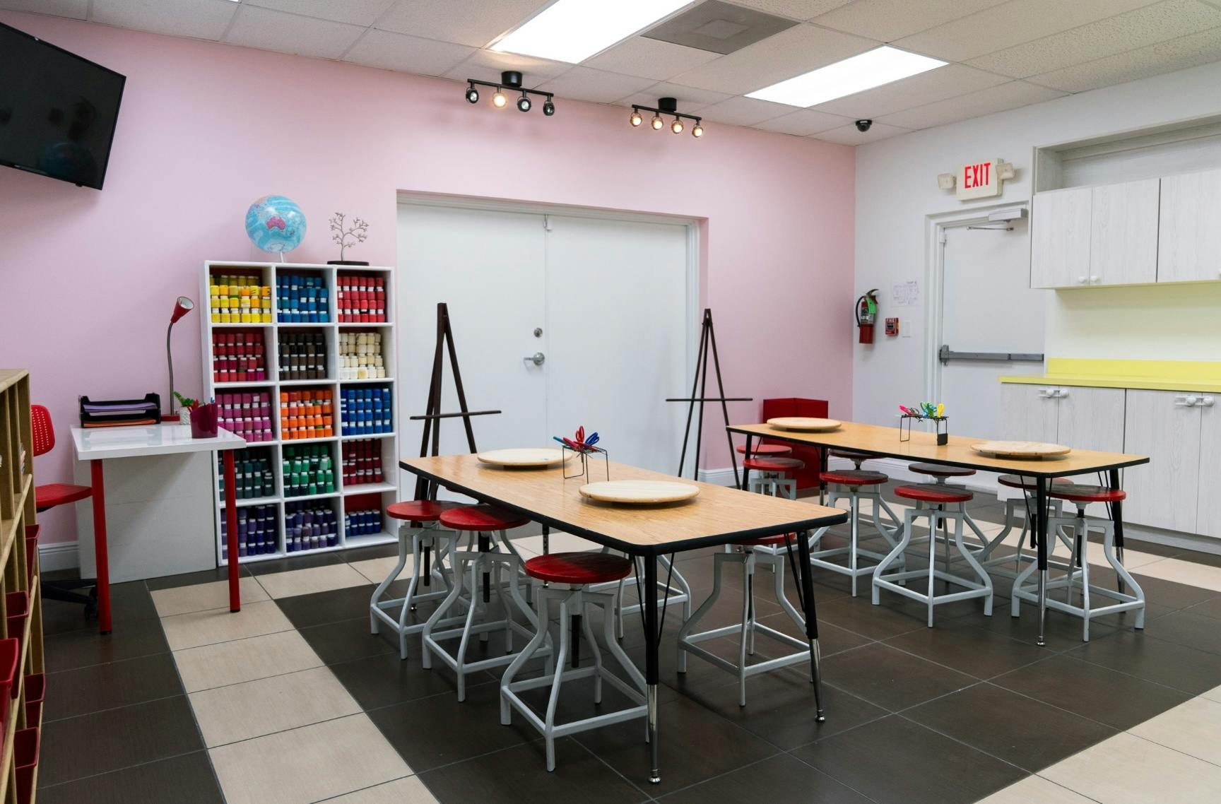 Art studio with tables, stools, easels, and shelves of art supplies