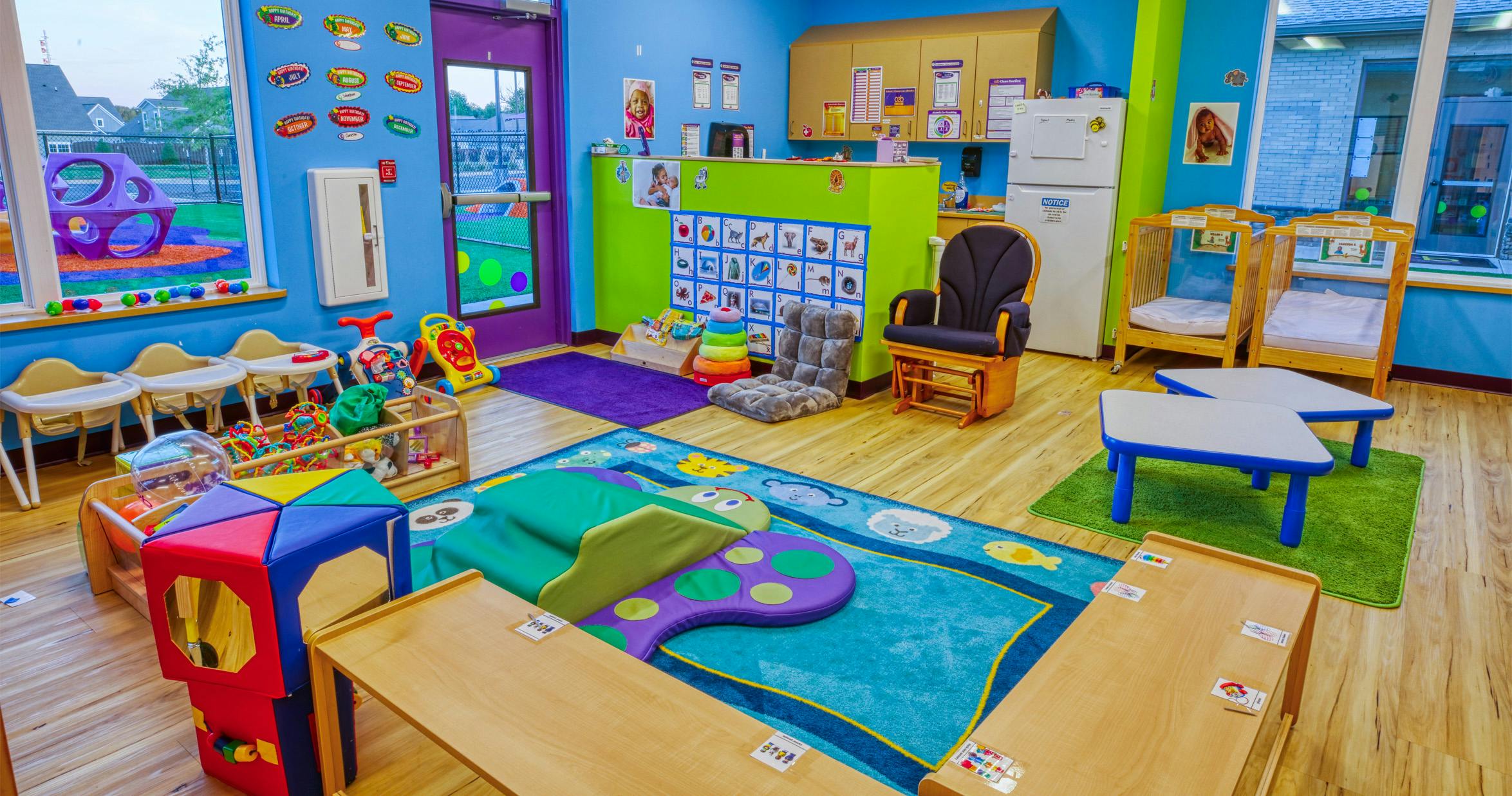 Colorful daycare room with cribs, small tables, and play mats