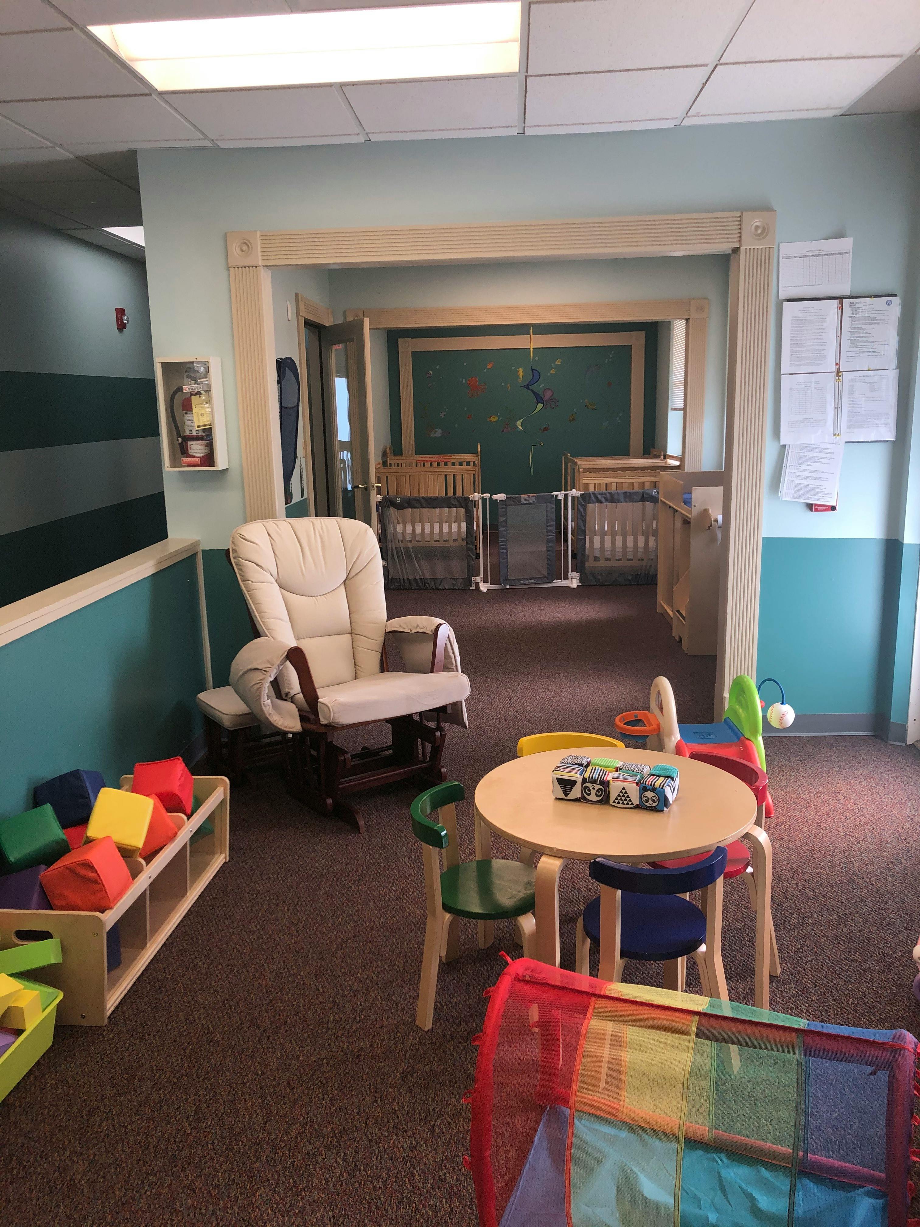 Nursery room with a rocking chair, small table and chairs, and cribs