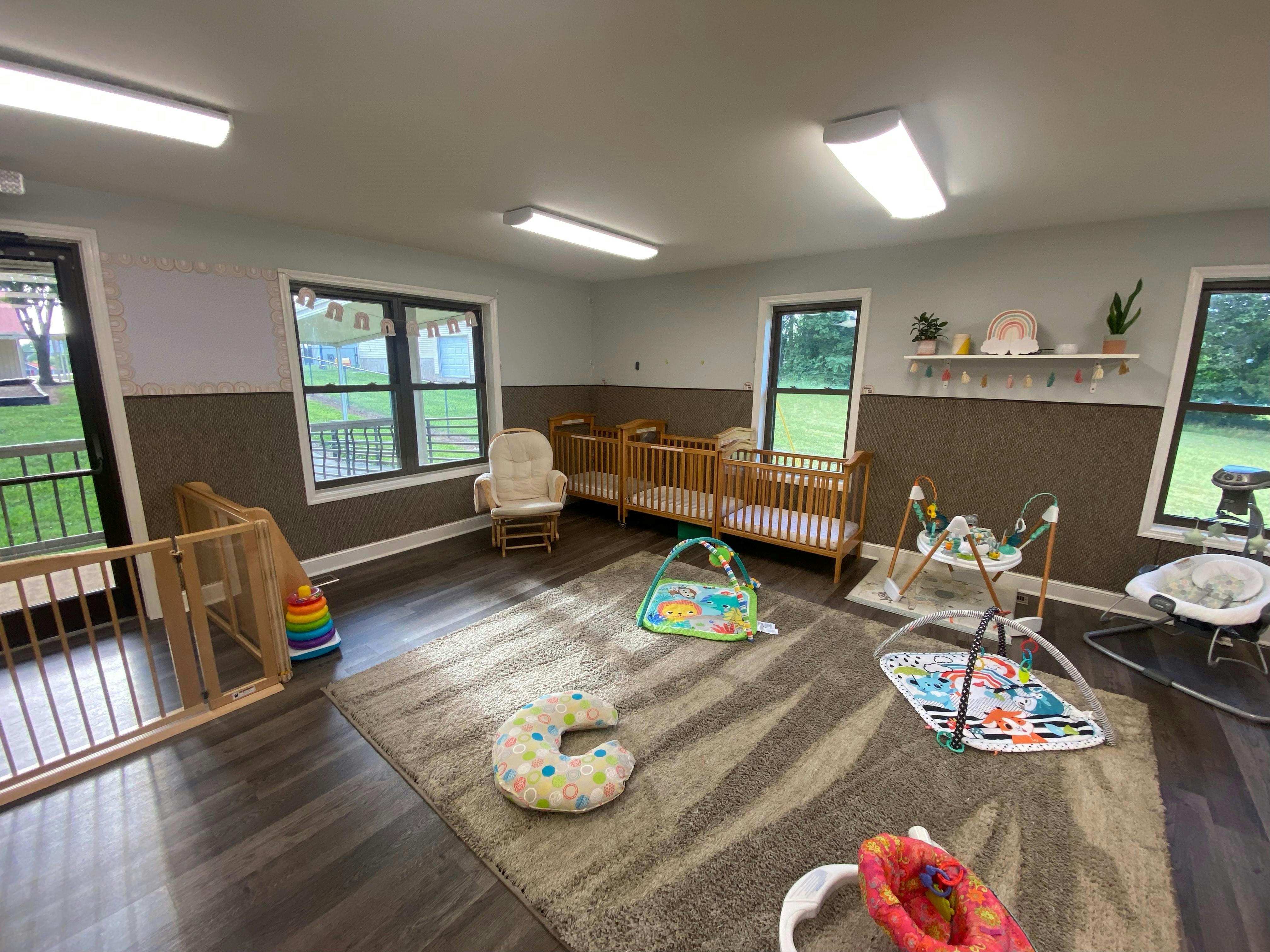 Baby room with cribs, play mats, a rocking chair, and a baby gate