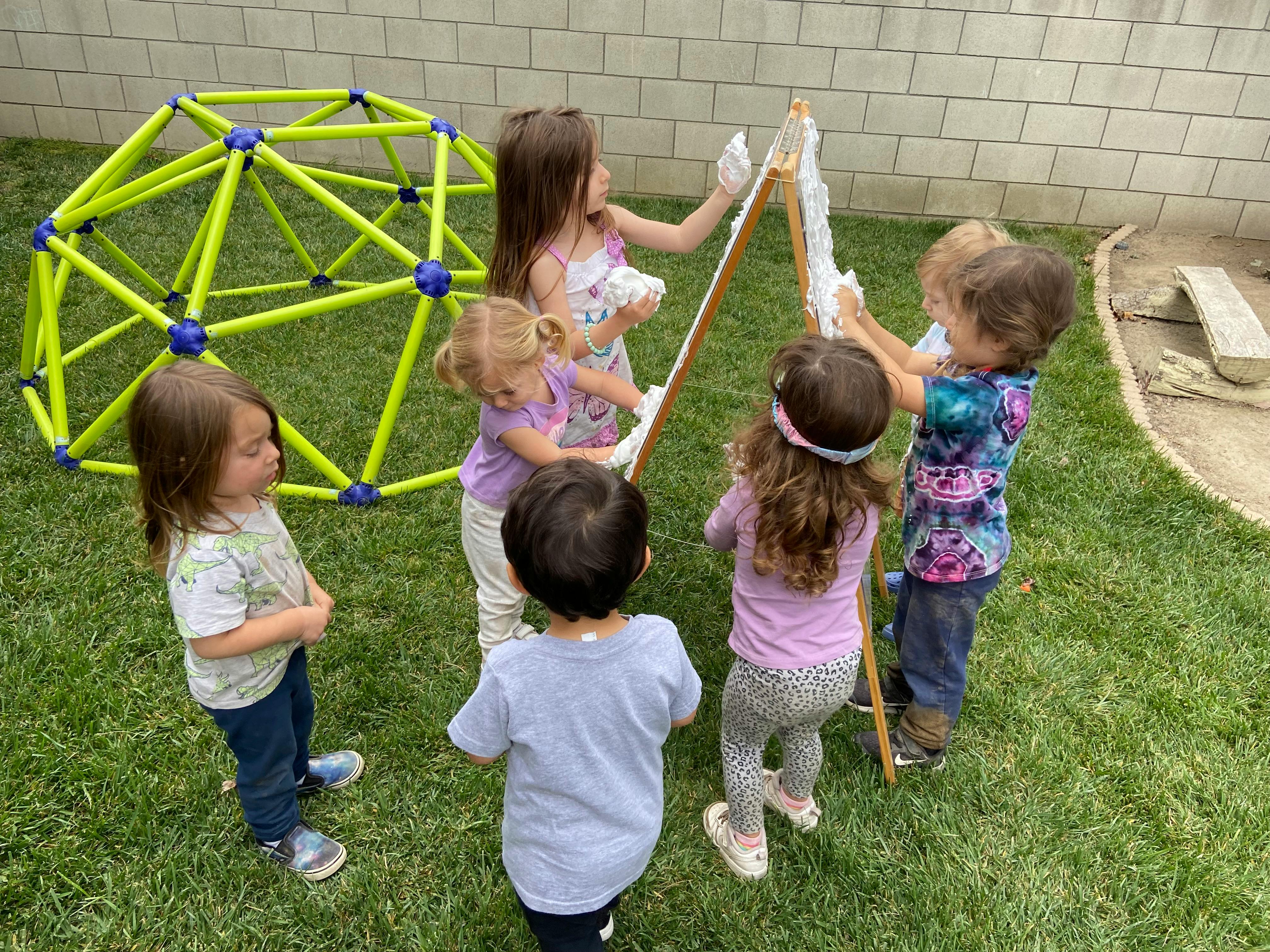 Children painting on an easel outdoors