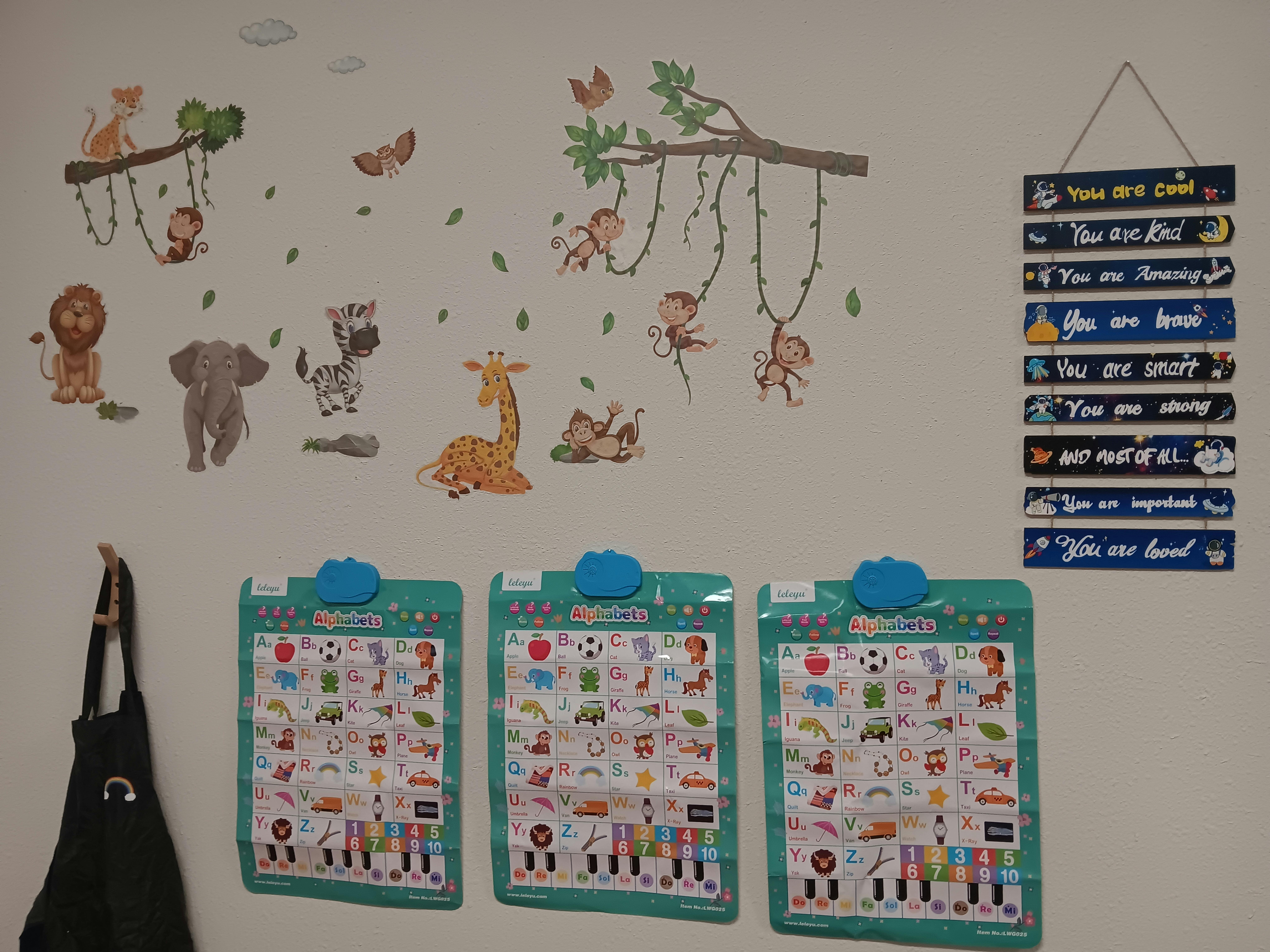 Wall with animal decals, three charts, and a hanging sign with positive affirmations