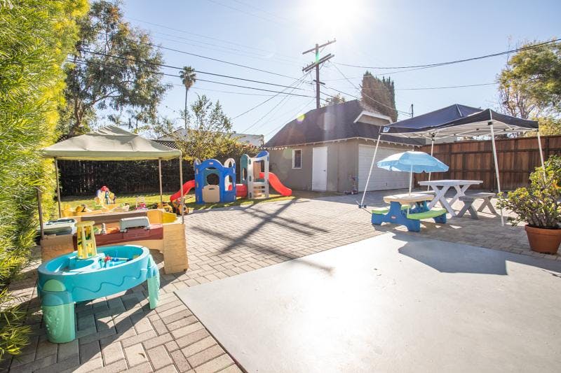 Outdoor play area with slides, tables, and canopies