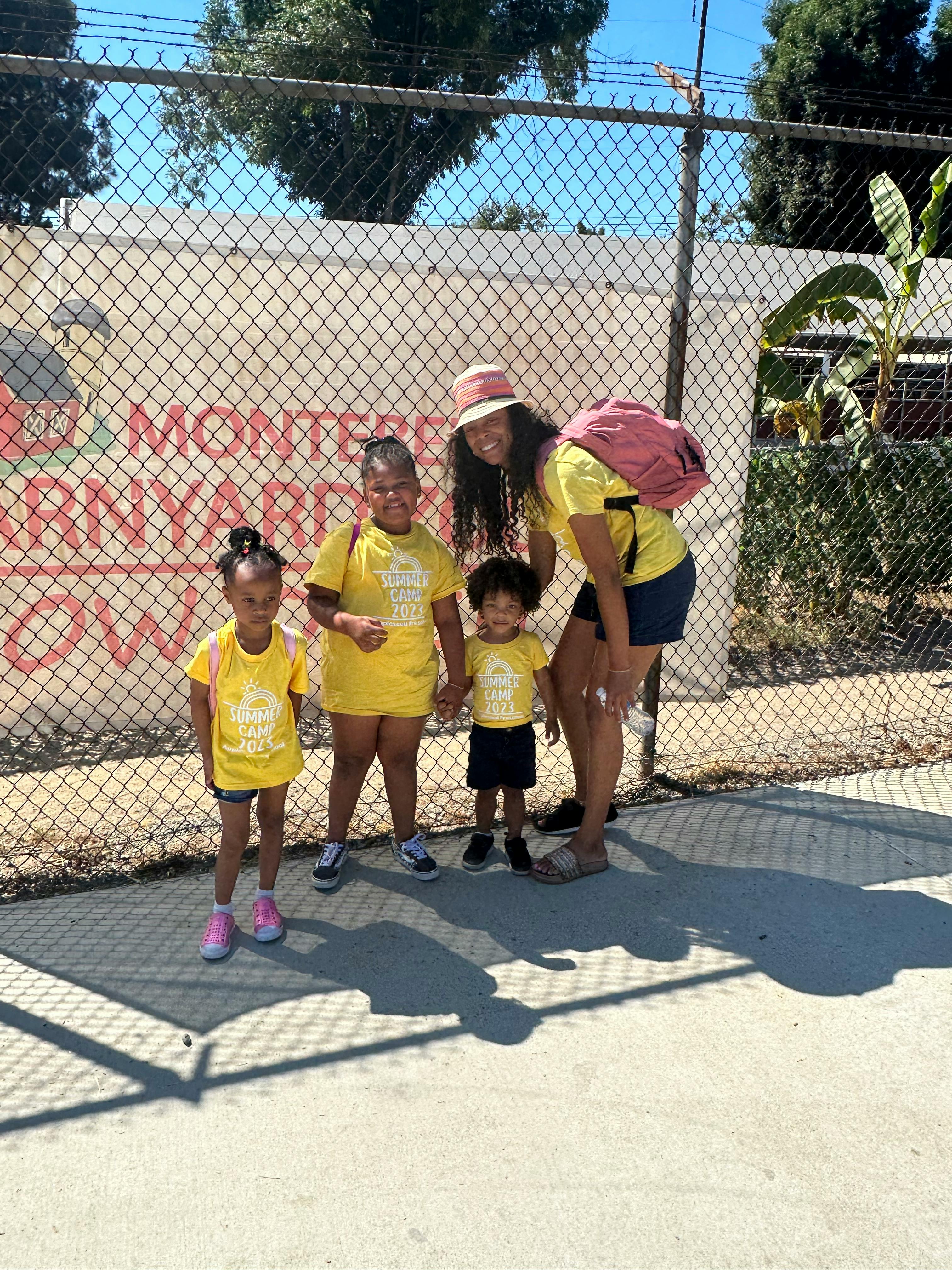 Person with three children standing in front of a fence