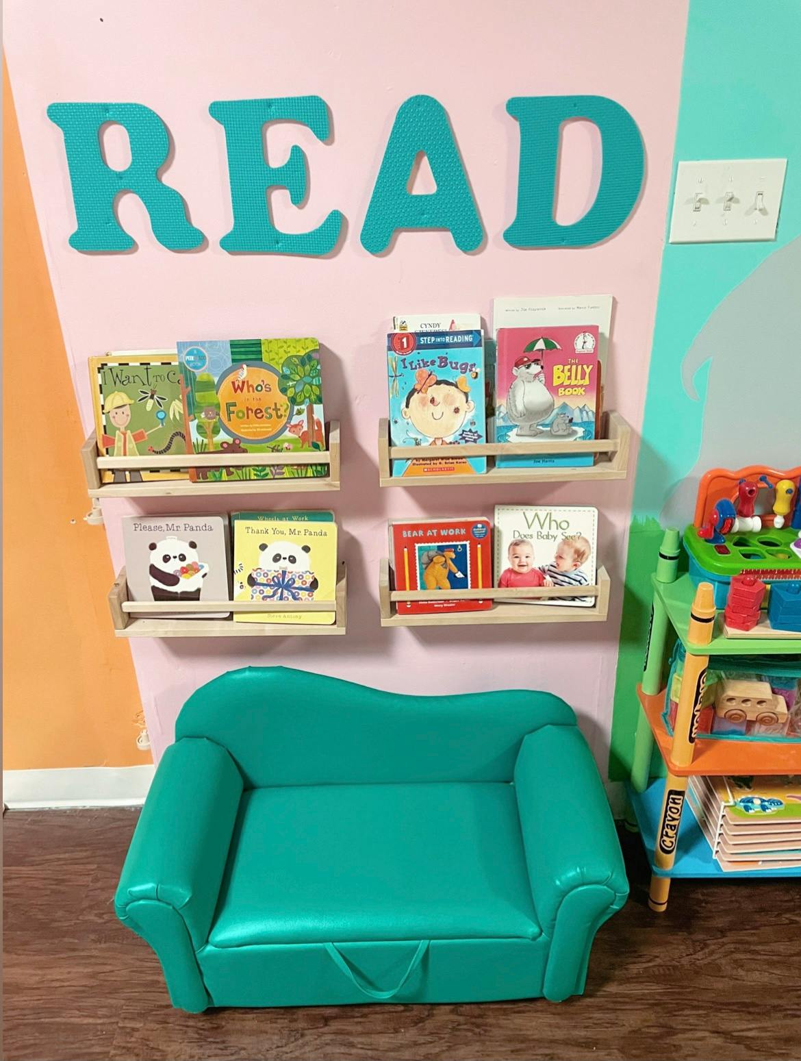 Children's reading nook with a small teal couch and bookshelves with books