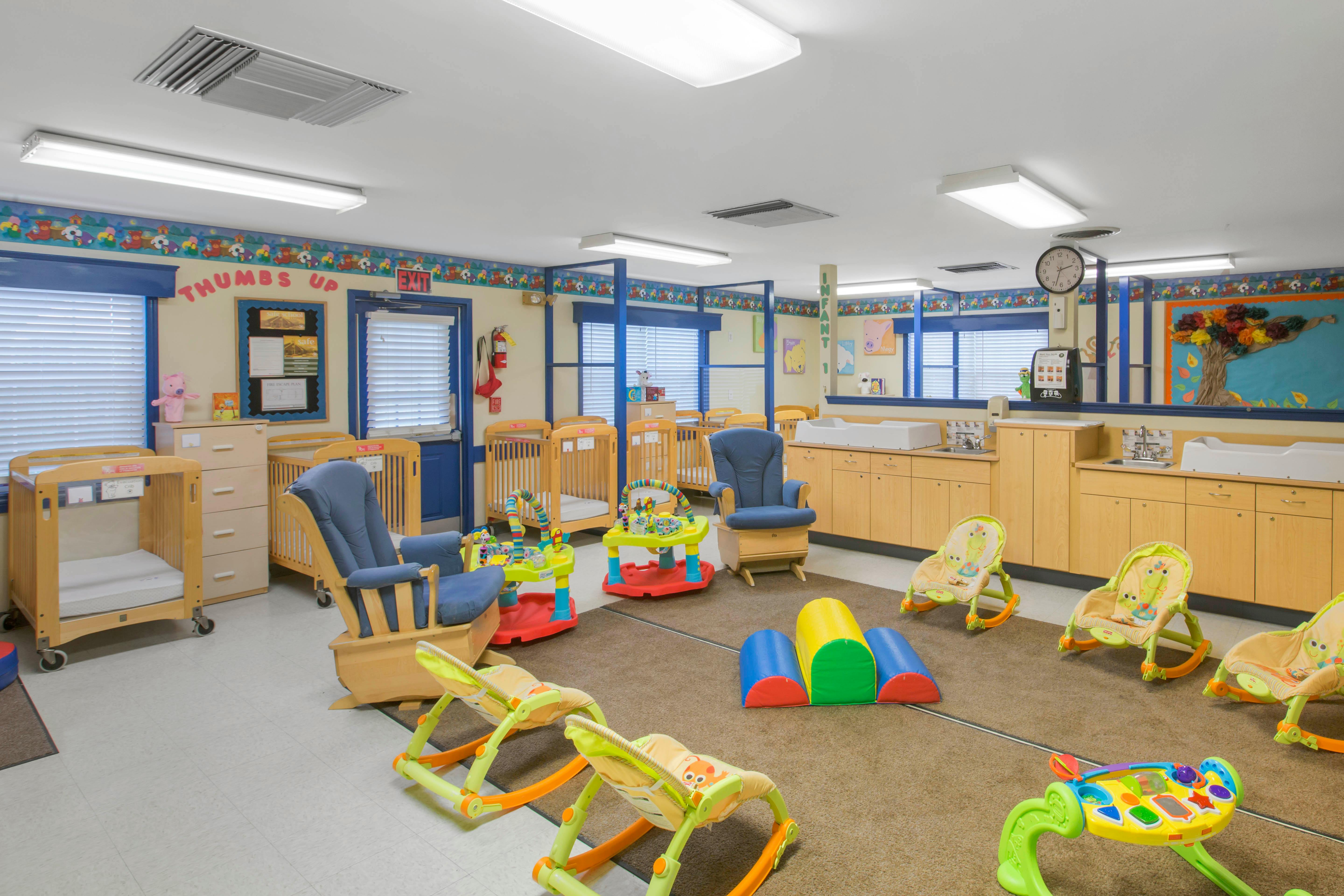 Infant nursery with multiple cribs, a changing station, and baby play equipment