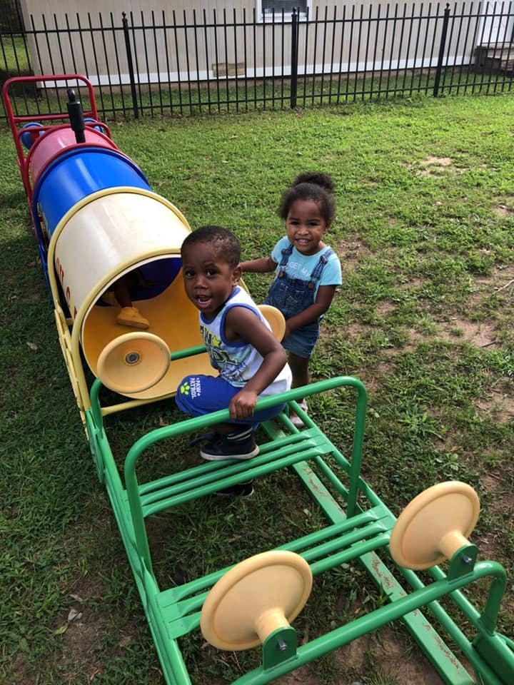 Two children playing on a train-shaped playground structure