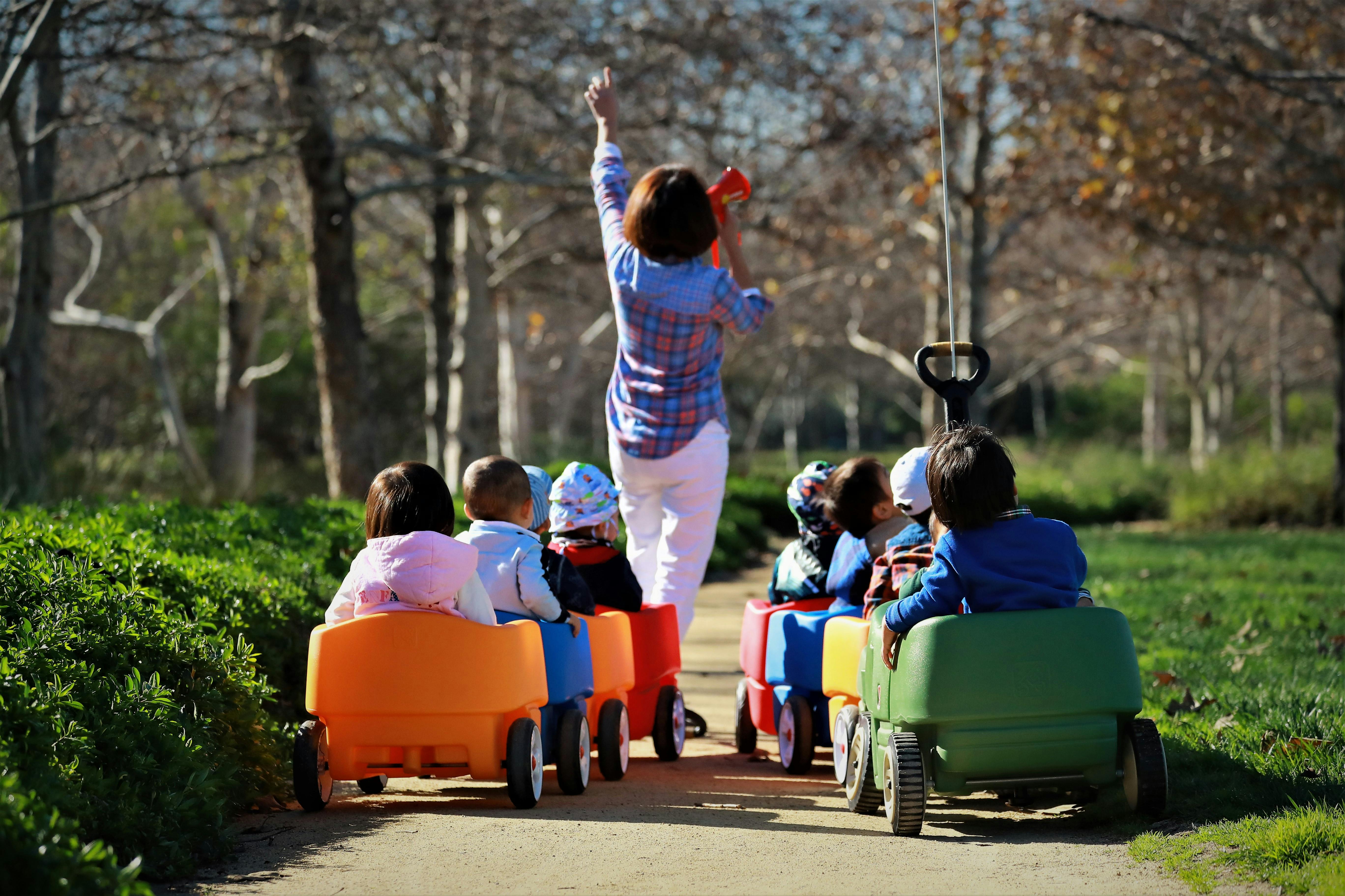 Person leading children in wagons