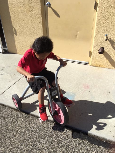 Child riding a tricycle on a sidewalk