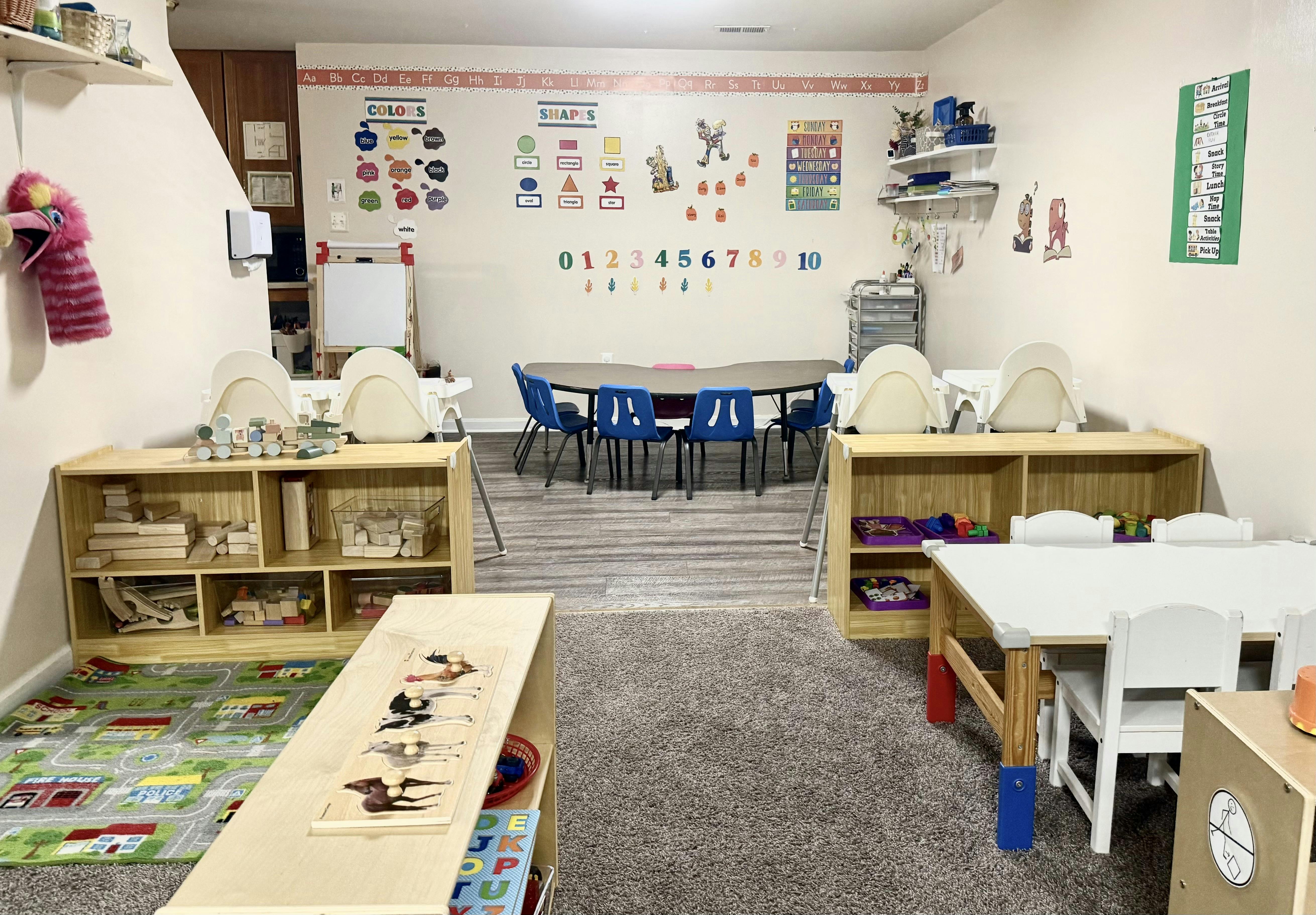 Classroom with small tables and chairs, shelves with learning materials