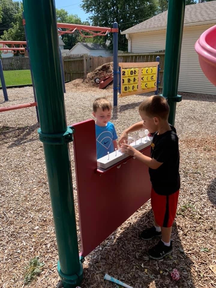 Two children playing with a musical instrument on a playground