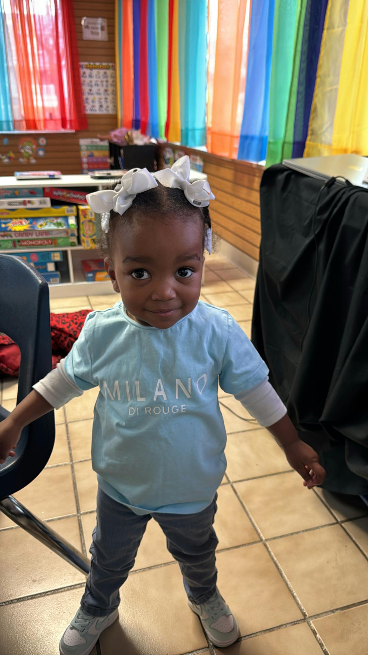 child in a light blue shirt standing in a classroom