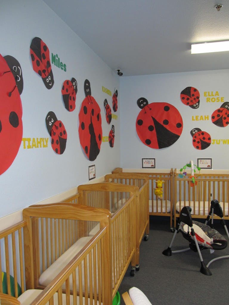 Nursery room with multiple wooden cribs and ladybug wall decorations