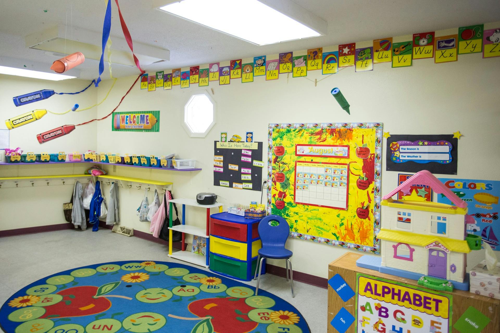 Empty classroom with colorful decorations, a round rug, and small furniture