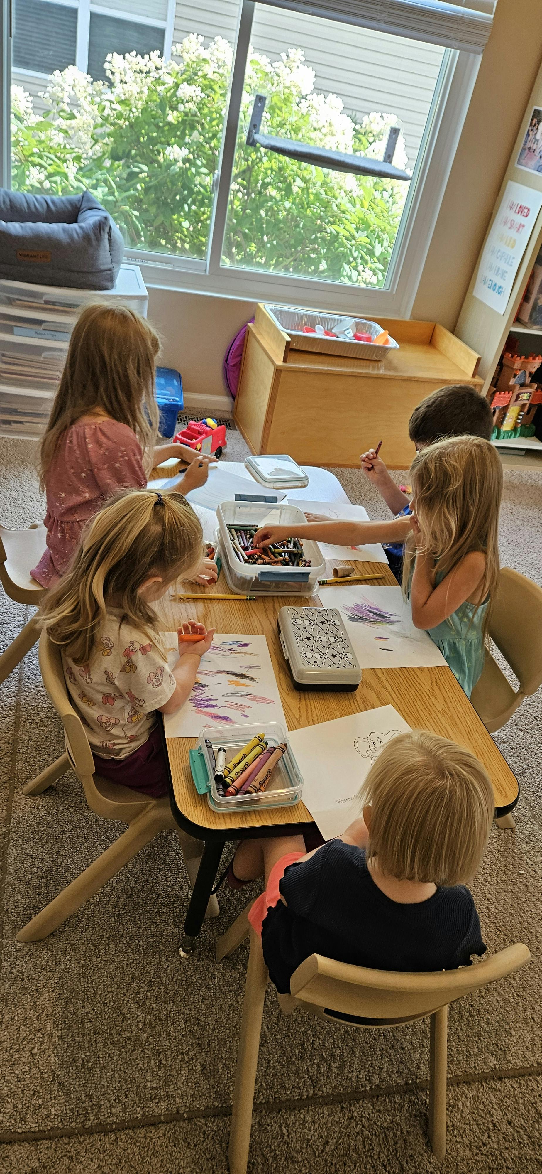 Children drawing and coloring at a table in a classroom