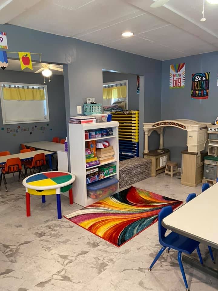 A colorful classroom with small tables, chairs, and a bookshelf