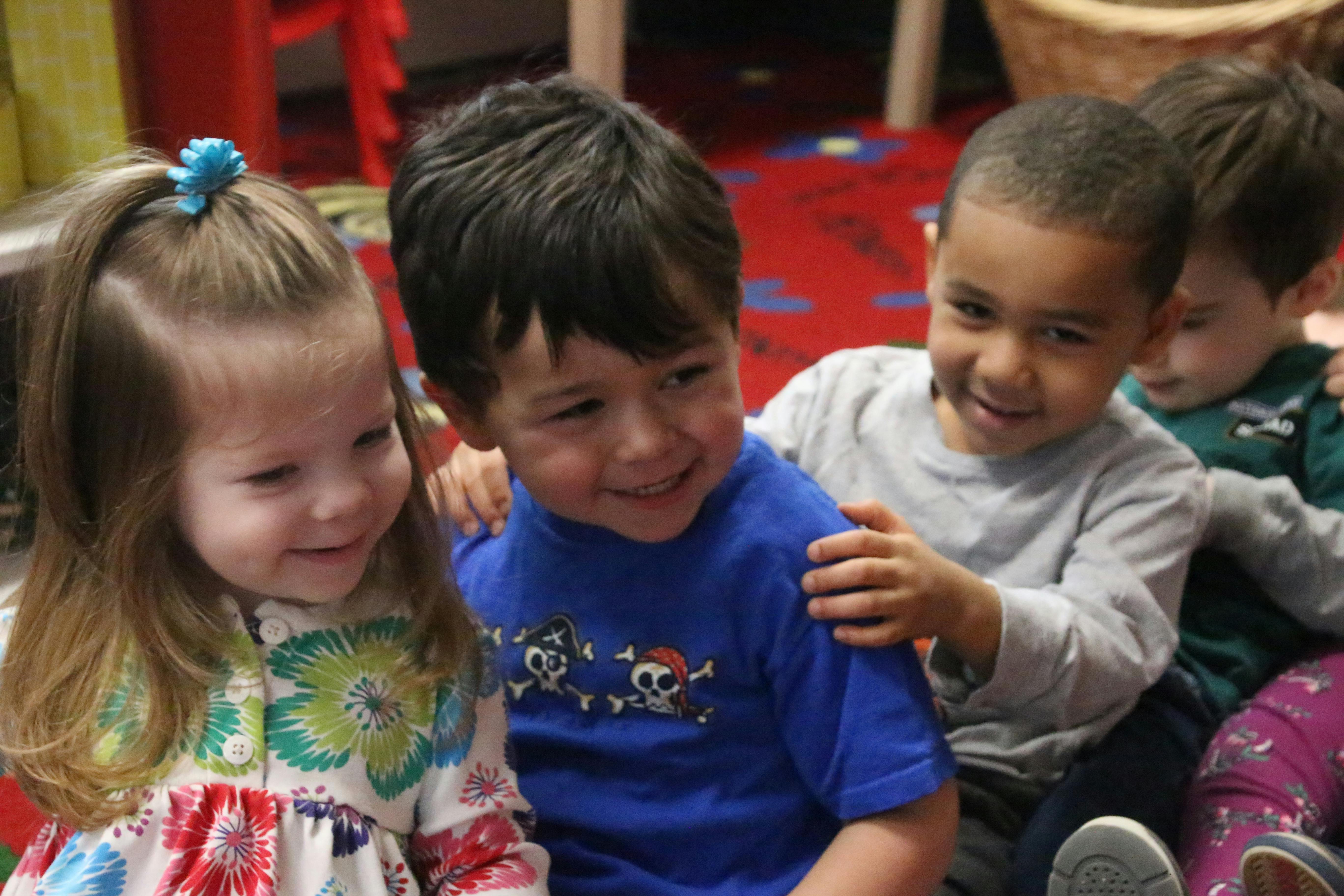 Four children sitting together, one child with hand on another's shoulder