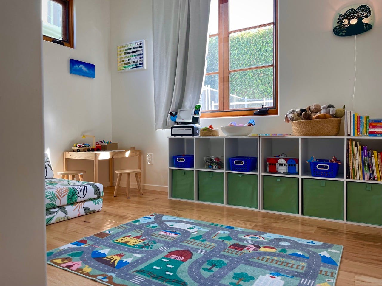 Children's playroom with a road map rug, small table, and toy storage shelves