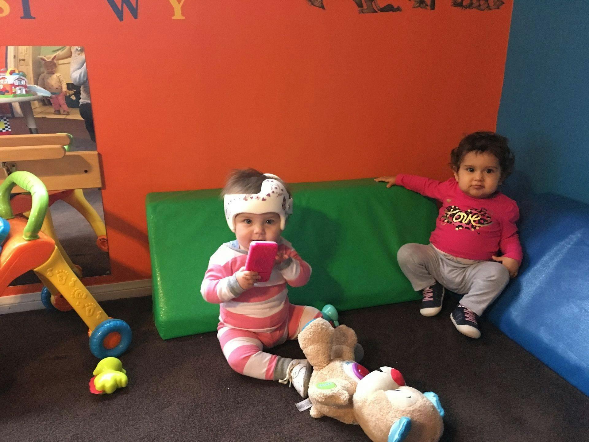 Two children sitting on the floor, one holding a pink object