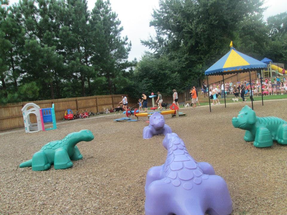 People and children on a playground with animal-shaped play structures