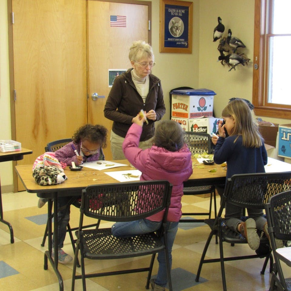 Adult person supervising three children at a table