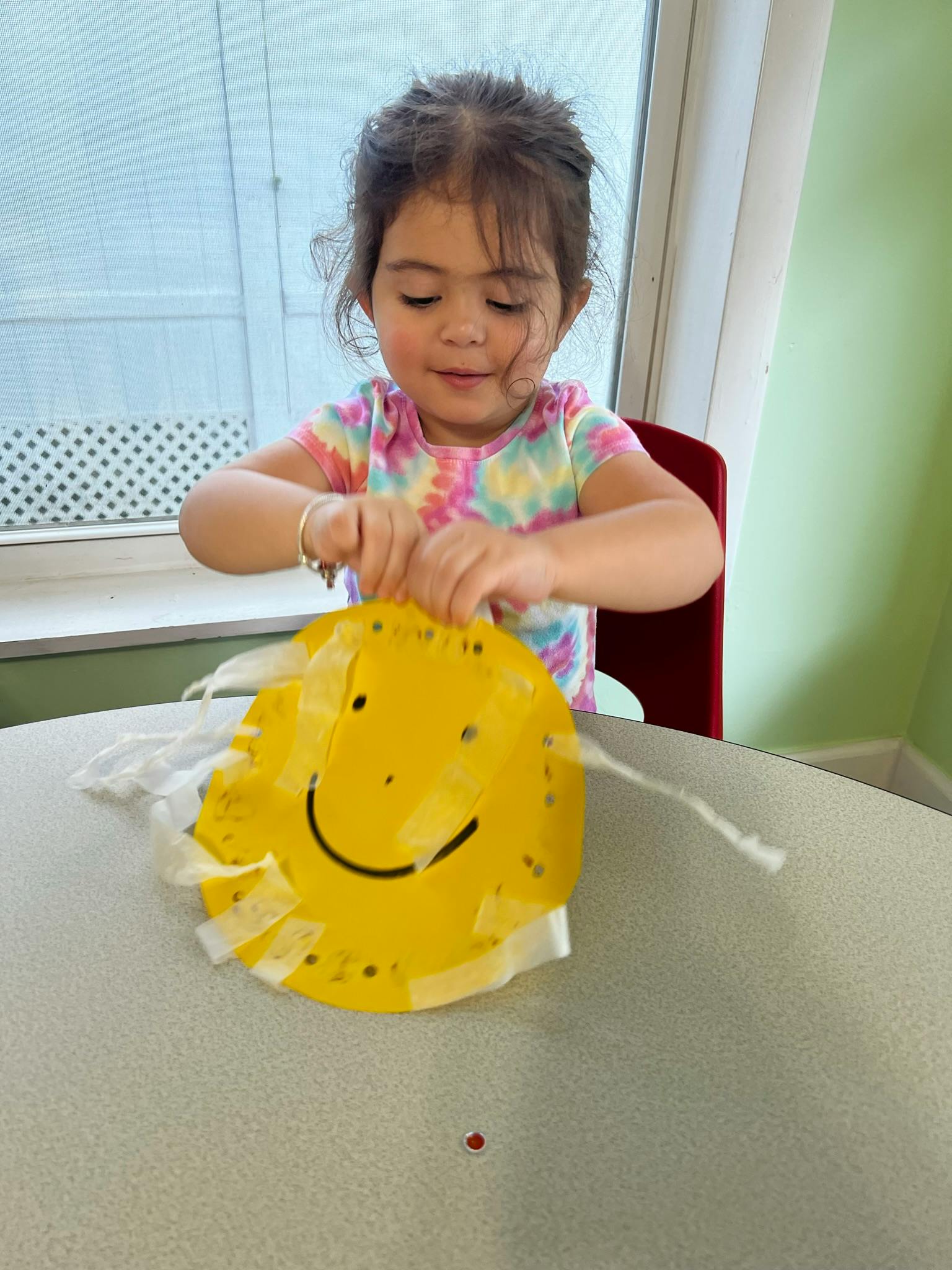 Child making a craft with a yellow paper plate