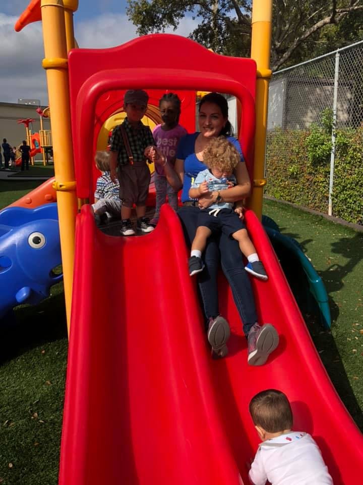 Adult and children on a red playground slide