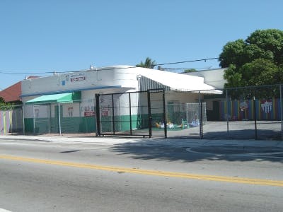 Building with a green and white facade and a fence in front of it
