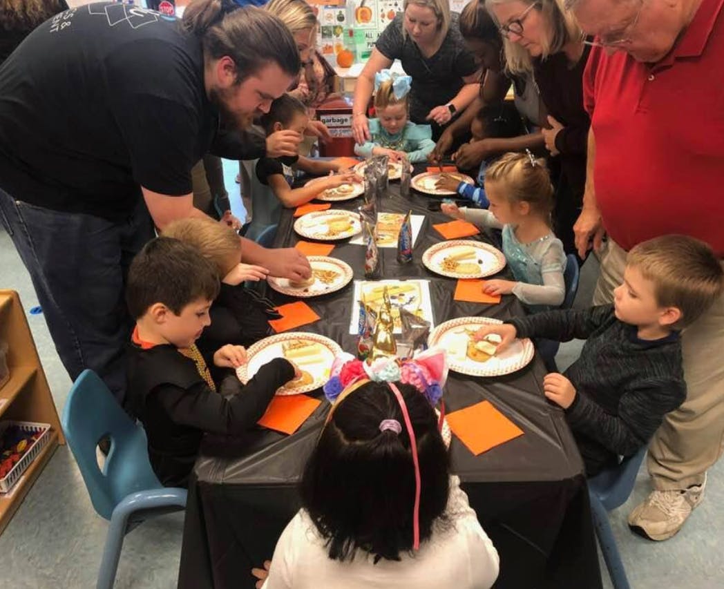 Adults helping children at a table with plates